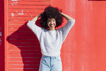 Cheerful woman standing with hand in hair on sunny day - MEUF02912