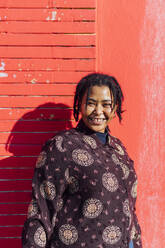 Frau lächelnd vor einer roten Wand stehend - MEUF02922