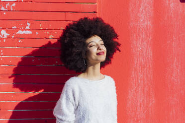 Afro Haar Frau lächelnd vor roter Wand stehend - MEUF02923