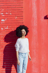 Afro-Haar Frau Tag träumen, während stehend vor der roten Wand - MEUF02927