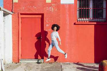 Happy young woman jumping on footpath - MEUF02941