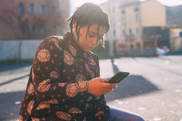 Junge Frau benutzt Mobiltelefon an einem sonnigen Tag - MEUF02948