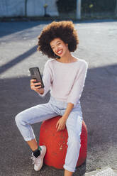Lächelnde Frau, die ein Selfie mit ihrem Smartphone auf dem Fußweg macht - MEUF02952