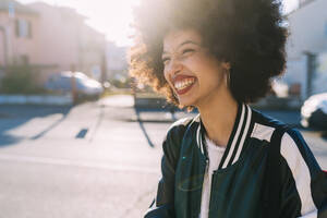 Curly hair woman smiling while looking away - MEUF02980