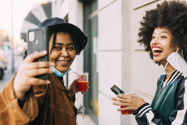 Friends with face masks taking selfie through smart phone - MEUF03000