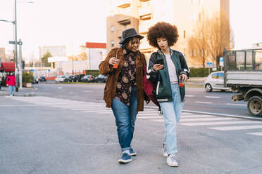 Young women using mobile phone while walking on phone - MEUF03004
