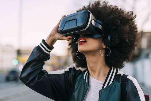Young afro hairstyle woman using virtual reality headset - MEUF03013