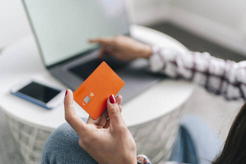 Woman with credit card doing online shopping through laptop at home - DGOF02243