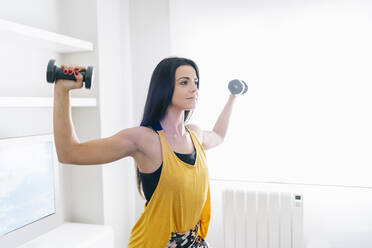 Young woman exercising with hand weight at home - DGOF02265