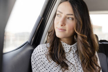 Schöne Geschäftsfrau schaut weg, während sie im Auto sitzt - FMOF01383