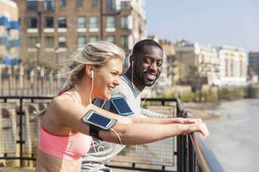 Smiling man and woman leaning on railing while exercising - WPEF04576
