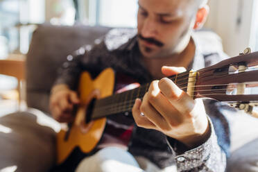 Junger männlicher Gitarrist spielt Gitarre zu Hause - MEUF03017