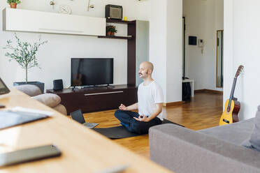 Junger Mann lernt Online-Yoga über seinen Laptop zu Hause - MEUF03051