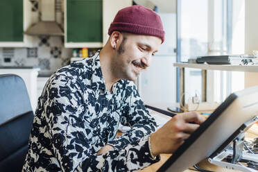 Smiling man using graphics tablet at home - MEUF03060