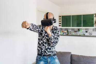 Junger Mann trägt Virtual-Reality-Simulator und schlägt zu Hause zu - MEUF03062