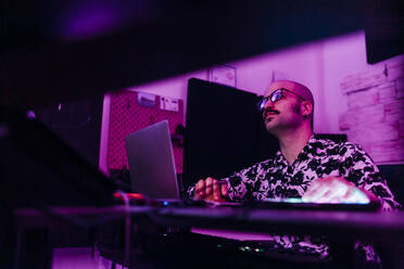 Male composer wearing eyeglasses composing music at studio - MEUF03085