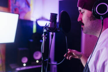 Mann mit geschlossenen Augen gestikuliert beim Singen im Heimstudio - MEUF03091