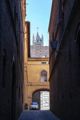 Italien, Toskana, Siena, Leere Gasse mit Glockenturm des Doms von Siena im Hintergrund - MAMF01841