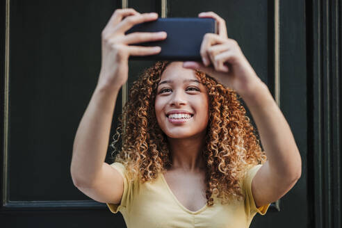 Lächelnde Frau nimmt Selfie durch Smartphone - EBBF03679