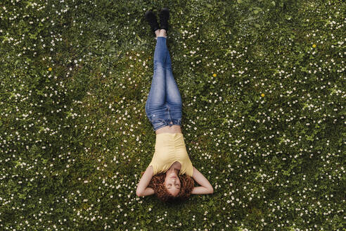 Junge Frau schläft auf einer Wiese inmitten von Blumen - EBBF03717