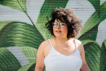 Inhalt Erwachsene übergewichtige Frau mit Brille lockiges Haar gegen ornamentale Wand in der Tageszeit - ADSF24597