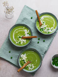 Top view of delicious pea cream soup in bowls served on table with napkin and vase with flowers - ADSF24602
