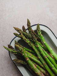 Top view of bunch of fresh green asparagus placed in bowl on table - ADSF24608