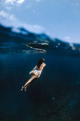 Weibliche Touristin im Badeanzug schwimmt im sauberen, transparenten Meer während des Urlaubs in einem sonnigen tropischen Urlaubsort - ADSF24662