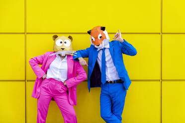 Man and woman wearing vibrant suits and animal masks posing side by ...