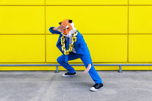 Mann in leuchtend blauem Anzug und Tigermaske steht in Kampfstellung vor einer gelben Wand - OIPF00767