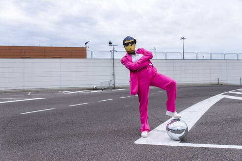 Lustige Figur mit Tiermaske und rosa Business-Anzug, die sich auf einem leeren Parkplatz amüsiert - OIPF00821