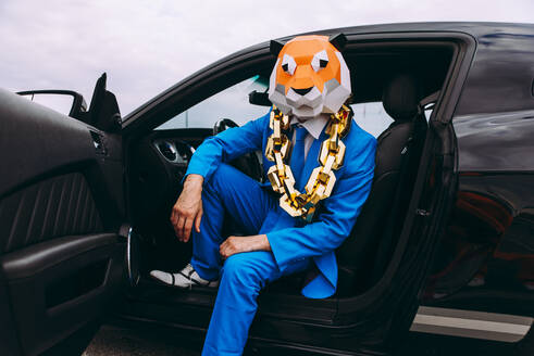 Lustige Figur in Tiermaske und blauem Geschäftsanzug im Auto sitzend - OIPF00825