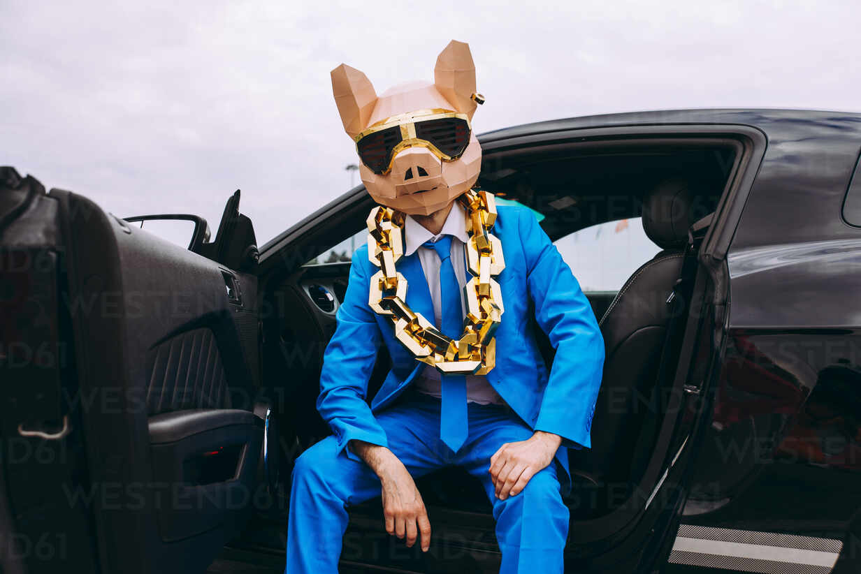 Lustige Figur in Tiermaske und blauem Business-Anzug sitzt im Auto,  lizenzfreies Stockfoto
