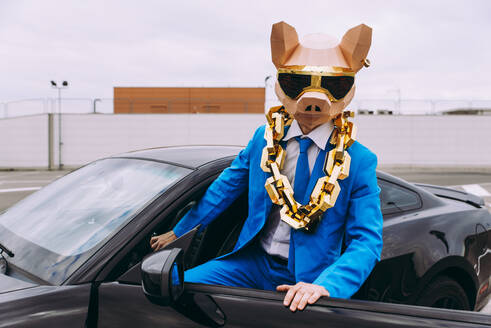 Lustige Figur mit Tiermaske und blauem Geschäftsanzug, die ins Auto steigt - OIPF00829