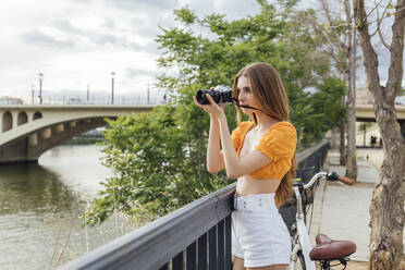 Woman photographing through camera by railing - JRVF00776