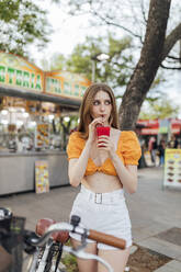 Woman looking away while drinking juice on street - JRVF00780