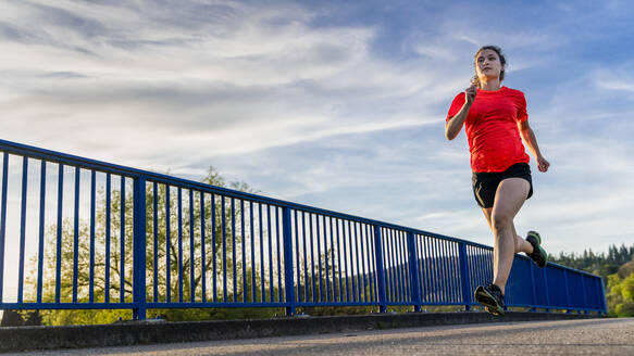 Junge Frau beim Joggen auf der Brücke - STSF02961