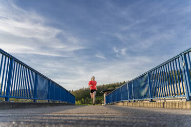 Junge Frau beim Joggen auf der Brücke - STSF02962