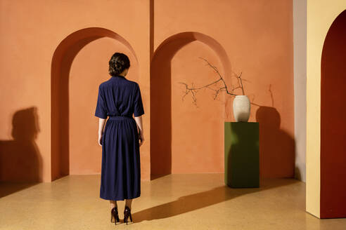 Woman standing in front of orange wall with arches - VPIF04039