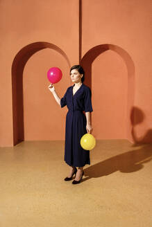 Woman holding balloons in front of wall with arches - VPIF04041