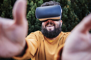 Lächelnder Mann mit Virtual-Reality-Simulator im Garten - ASGF00315
