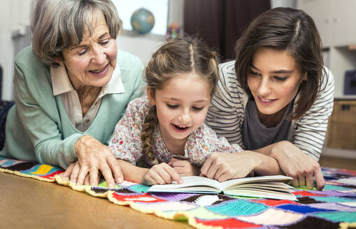 Ein Mädchen liest ein Buch und liegt neben einer Frau im Kinderzimmer - AUF00636