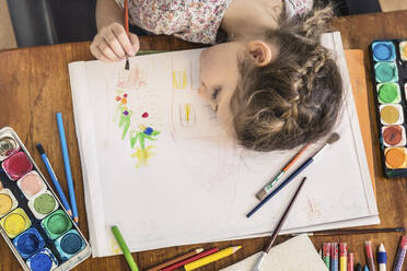 Tired girl with paintbrush leaning on table at home - AUF00643