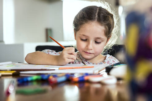 Nettes Mädchen malt mit Pinsel auf Papier zu Hause - AUF00644