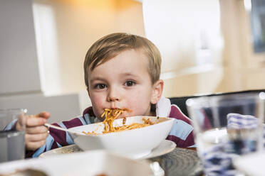 Niedlicher Junge starrt beim Essen zu Hause - AUF00672