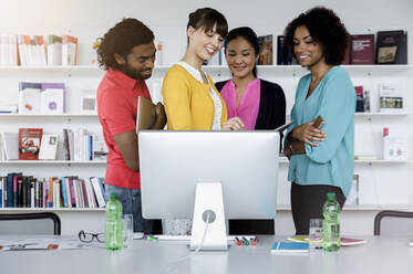 Smiling male and female entrepreneurs working in front of computer at office - BMOF00729