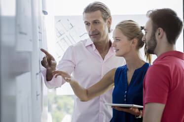 Male and female professional discussing over blueprint in office - BMOF00744