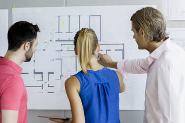 Male and female design professionals working on blueprint in office - BMOF00746