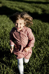 Cheerful little girl running on agricultural field during sunny day - RCPF01089