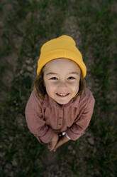 Lächelndes süßes Mädchen mit Strickmütze auf einem landwirtschaftlichen Feld - RCPF01098